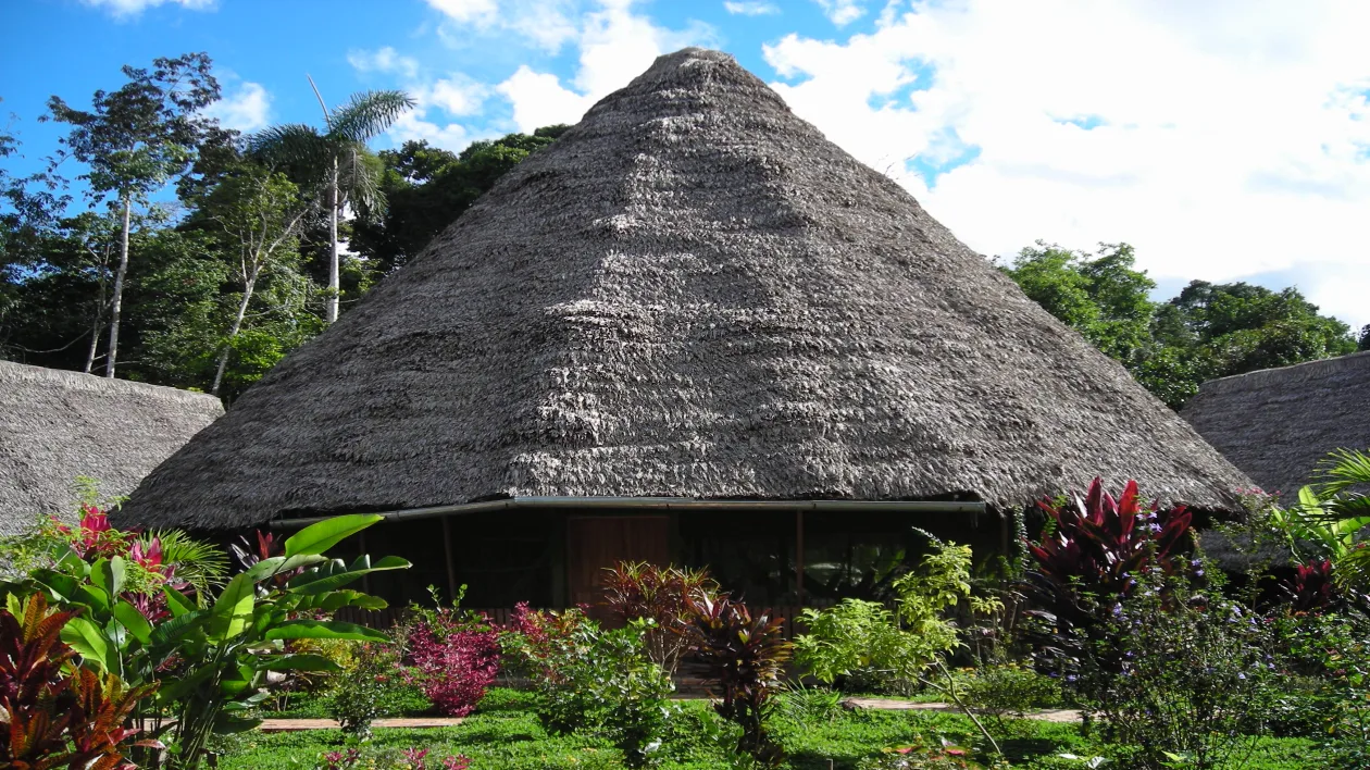 An ayahuasca ceremonial maloca structure surrounded by lush Amazon jungle vegetation, representing the retreat environment that participants return home from during the integration period.